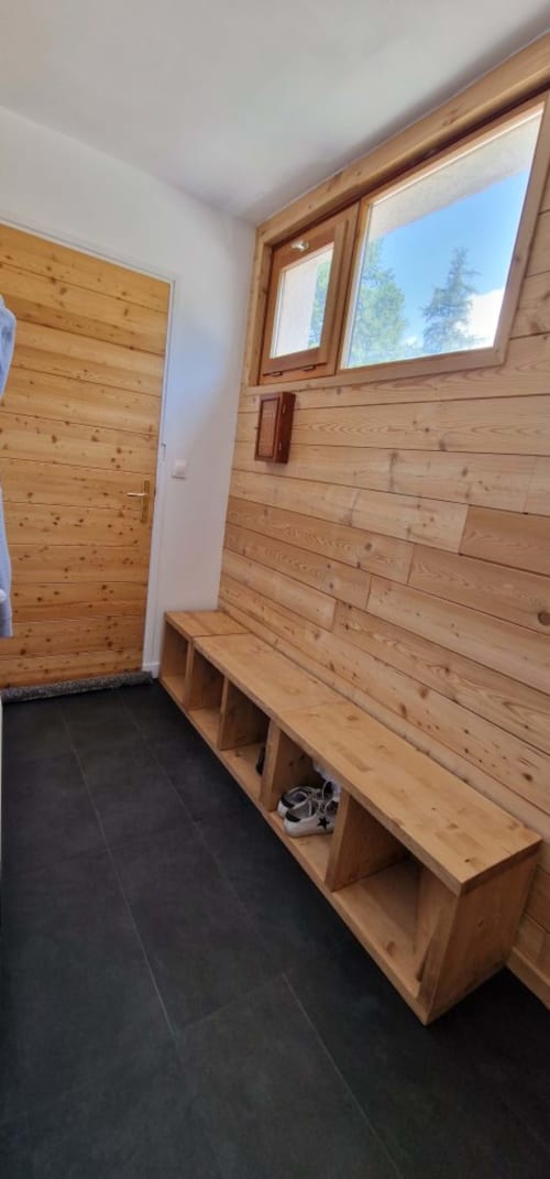 "Hall d'entrée de l'appartement à Vars-les-Claux, décoré en bois chaleureux, avec un espace dédié pour déposer les chaussures de ski, offrant praticité et confort dès l'arrivée à l'appartement après une journée sur les pistes."