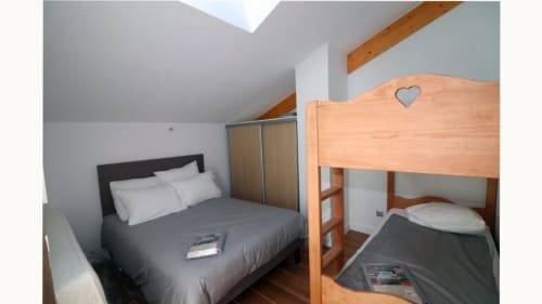 Chambre de l'appartement à Vars-les-Claux, équipée d'un lit double et de deux lits superposés, idéale pour accueillir une famille ou un groupe d'amis, offrant confort et fonctionnalité pour un séjour agréable