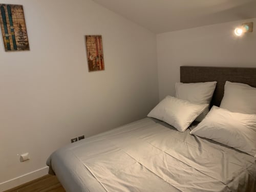 Chambre parentale de l'appartement à Vars-les-Claux, équipée d'un lit double confortable et d'une salle de bain privée, offrant un espace intime et chaleureux pour se détendre après une journée sur les pistes.