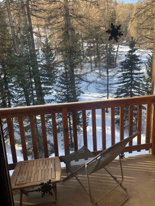 Balcon de l'appartement Albane B317 à Vars-les-Claux, équipé d'une petite table et de transats, parfait pour profiter du soleil et du paysage montagneux en toute tranquillité