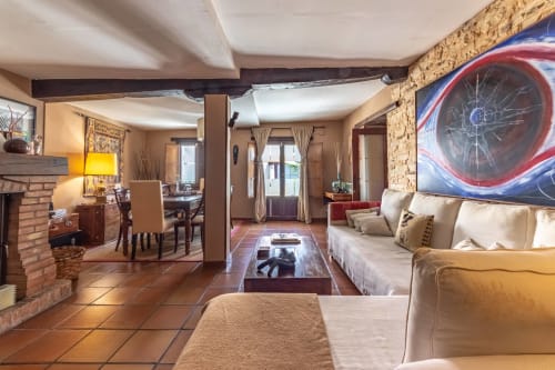 Spacieux séjour à Casa Peregrinando à Navarrete avec sols en terre cuite, canapés crème, cheminée et œuvres d'art contemporain