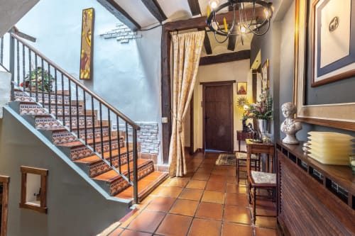 Entrée de Casa Peregrinando à Navarrete avec carrelage en terre cuite, escalier en bois et architecture rustique espagnole