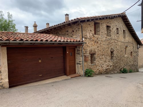 Casa de piedra rústica Casa Tapiolas en Molló, Girona con tejado de barro y puerta de garaje de madera
