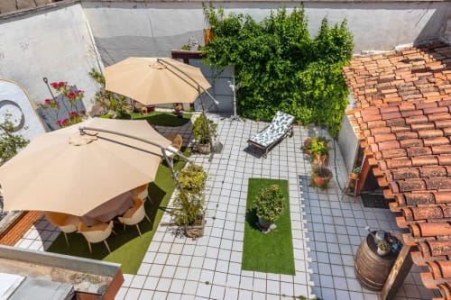 Terrasse sur le toit de Casa Peregrinando à Navarrete avec parasols, places assises, verdure et architecture en briques