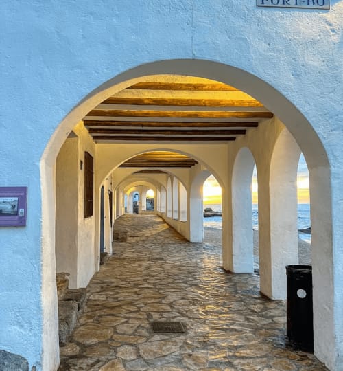 Covered beachfront archway at Finques Garcia Enrich in Palafrugell, Spain, with ocean views through white columns