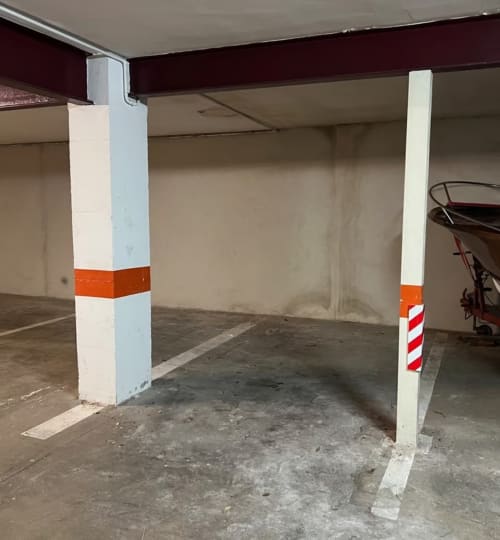 Underground parking garage at Finques Garcia Enrich hotel in Palafrugell with white columns marked with red and white stripes