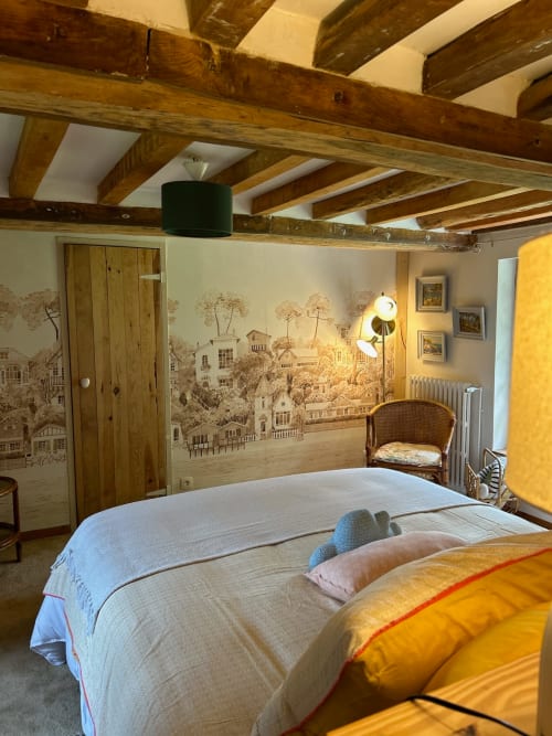 Chambre rustique aux poutres en bois apparentes, fresque murale décorative et accents jaunes au Domaine de Blanvatel