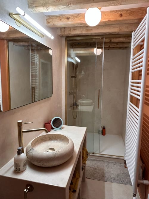 Salle de bain moderne au Domaine de Blanvatel avec lavabo en pierre, douche à l'italienne, sèche-serviettes chauffant et poutres apparentes