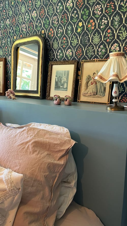 Chambre élégante du Domaine de Blanvatel avec papier peint botanique, miroir doré, art vintage et literie crème.