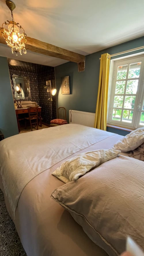 Elegant bedroom at Domaine de Blanvatel B&B with twin beds, teal walls, wooden beams, and garden views