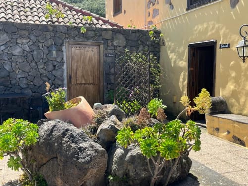 Patio de casa de piedra en Casonas de Marengo, Icod de los Vinos con puertas rústicas de madera, macetas de barro