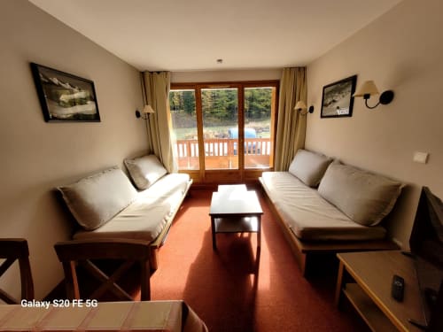 Salon de l'appartement B06 dans la résidence l'Albane à Vars-les-Claux, offrant un espace confortable avec vue directe sur le balcon, parfait pour profiter du paysage montagneux et de l'air frais après une journée de ski