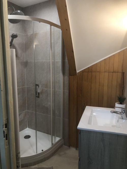 Salle de bain moderne avec douche à l'italienne, lavabo blanc et panneaux en bois à la Conciergerie Des Climats, appartement à Beaune
