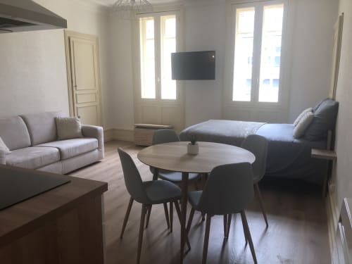 Studio moderne à Beaune avec canapé, table de salle à manger, lit, TV et vue sur la ville par portes-fenêtres