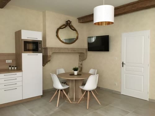 Salle à manger contemporaine dans un appartement à Beaune avec table ronde, chaises blanches, cuisine, cheminée et télévision écran plat