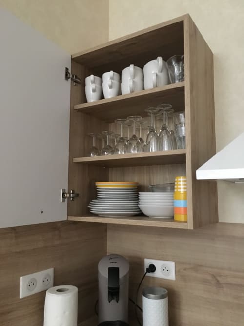 Vaisselier de cuisine avec vaisselle, verrerie et bougies blanches dans l'appartement de Beaune à la Conciergerie Des Climats