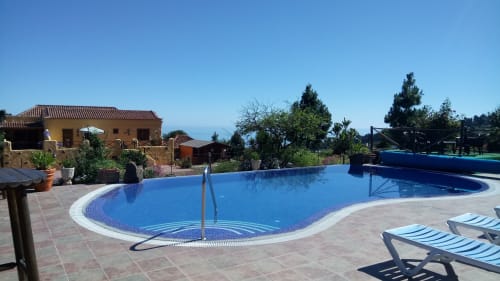 Curved blue swimming pool with loungers at Casonas de Marengo cottage in Icod de los Vinos, Tenerife