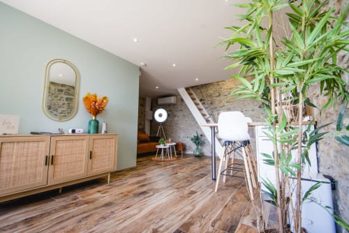 Intérieur de cottage moderne à La Romance avec parquet, mobilier en rotin et plantes de jardin à Bagard