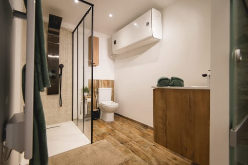 Salle de bain cottage moderne à La Romance avec douche à l'italienne, meuble vasque en bois, toilettes et vue sur le jardin à Bagard.