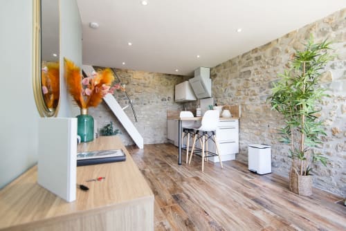 Cuisine chaleureuse à La Romance avec murs en pierre, parquet, électroménagers inox et vue sur le jardin à Bagard