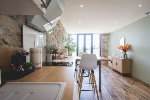 Cuisine-séjour moderne à La Romance avec murs menthe, comptoirs en bois et portes donnant sur le jardin