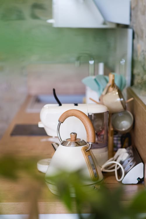 Bouilloire blanche avec poignée en bois sur le plan de travail de la cuisine du gîte La Romance à Bagard