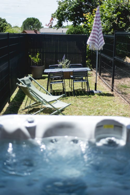 Le cottage Romance de Bagard avec sa table de jardin, parasol, transat et bain à remous
