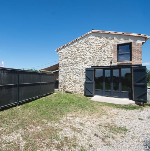 Façade de La Romance cottage à Bagard : murs en pierre, vue sur jardin et entrée noire moderne