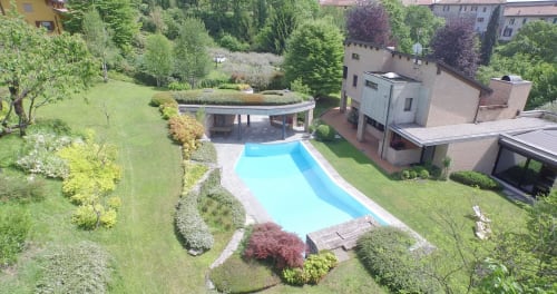 Piscina di Casa_B a Erba, Italia circondata da lussureggianti giardini e moderna architettura con palazzi residenziali