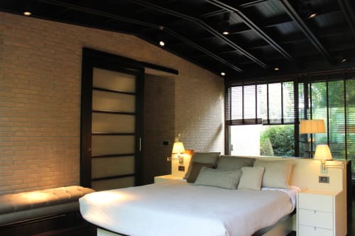 Camera moderna dell'appartamento Casa_B a Erba con muri in mattoni, letto platform e grandi finestre vista piscina