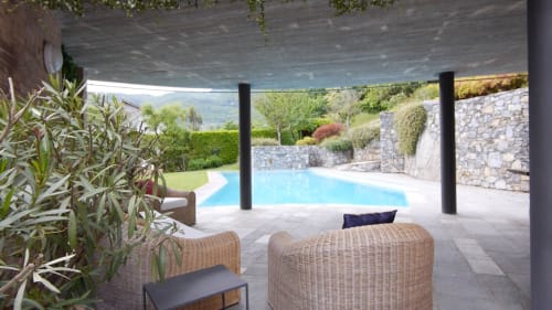Terrazza con vista piscina dell'appartamento Casa_B, arredamento in vimini, muri in pietra e rigogliosi giardini a Erba, Italia