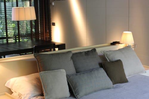 Camera da letto elegante dell'appartamento Casa_B a Erba con vista piscina, cuscini grigi, lampada da scrivania e illuminazione moderna