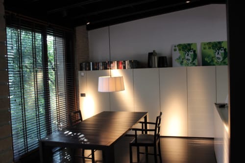Zona pranzo moderna a Casa_B Erba con porte jalousie, lampade a sospensione e arte contemporanea
