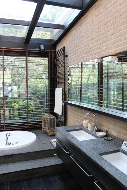 Bagno moderno nell'appartamento Casa_B a Erba con lucernario, doppi lavabi, vasca, muri in laterizio e vista sul giardino