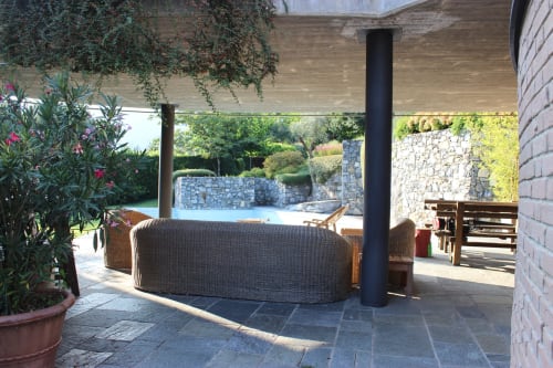 Patio dell'appartamento Casa_B con sedute in vimini, vista sulla piscina e giardini lussureggianti a Erba, Italia