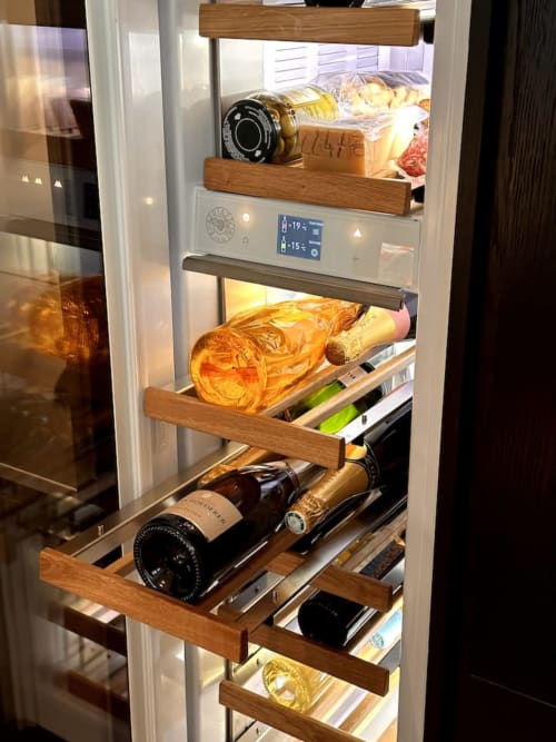Cantinetta integrata con scaffali in legno che conservano bottiglie e prodotti gourmet nell'appartamento Casa_B a Erba