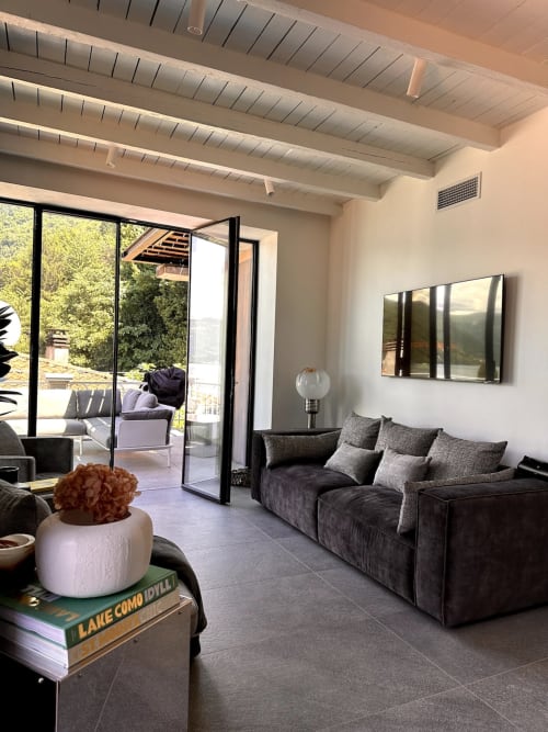 Soggiorno moderno di Casa_B a Erba con vista lago, divano scuro, travi a vista e accesso alla terrazza