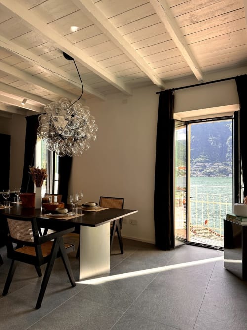 Sala da pranzo moderna di Casa_B a Erba con lampada a sospensione, tavolo nero e vista panoramica sul lago