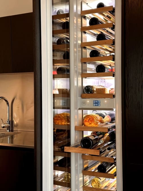 Cantina integrata con scaffali in legno che espongono bottiglie di vino presso l'hotel Casa_B a Erba, Italia