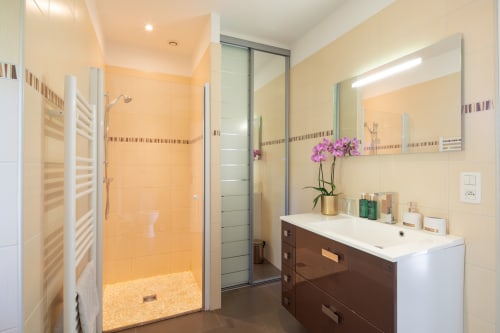 Moderne badkamer in gastenverblijf la Bergerie op Domaine De Campagnac met walk-in douche, wastafel en paarse orchidee