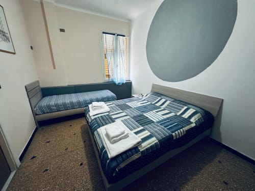 Due letti con biancheria a righe blu in una camera luminosa del Vecchie Mura B&B a Varazze, Italia, con design moderno