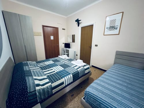 Camera doppia presso Vecchie Mura B&B a Varazze con letti a righe e porta-finestra con vista sul giardino