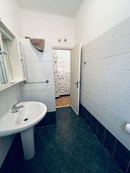 Bagno moderno della B&B Vecchie Mura a Varazze con piastrelle bianche, lavabo a colonna e pavimento scuro