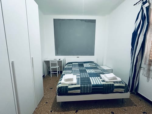 Camera accogliente a Vecchie Mura B&B a Varazze con biancheria rigata, pareti bianche e TV a parete