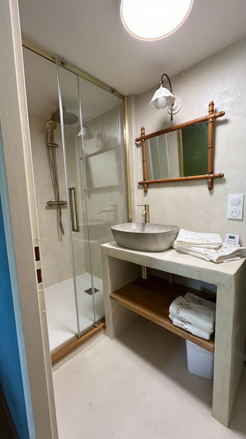 Salle de bain moderne du Domaine de Blanvatel avec douche vitrée, vasque en pierre, miroir en bois et sèche-serviettes électrique