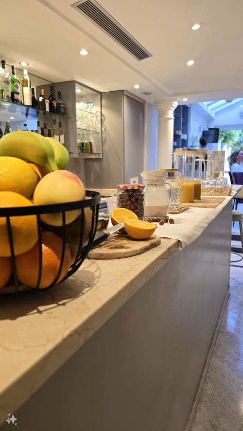 Buffet colazione dell'Hôtel De La Fontaine a Nizza con agrumi freschi, succhi e bevande su bancone in marmo