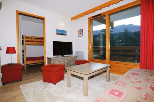 "Salon moderne et lumineux de l'appartement 301 à Vars-les-Claux, avec un balcon offrant une vue imprenable sur les montagnes enneigées, idéal pour se détendre après une journée de ski."