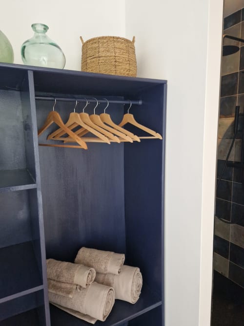 Armoire sombre avec cintres en bois et serviettes roulées à la Maisonaurinko B&B à Thénon