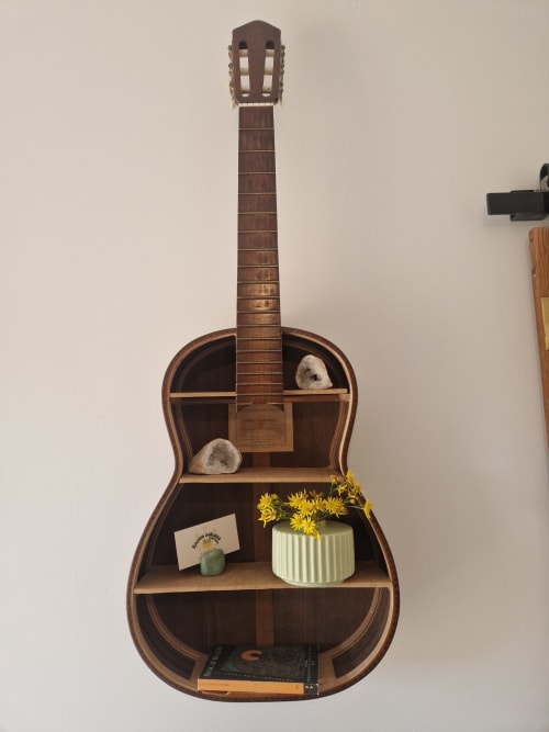 Étagère décorative en forme de guitare avec des livres et des fleurs jaunes dans la chambre de la Maisonaurinko, Thenon France