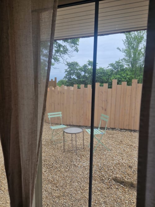 Terrasse du jardin Maisonaurinko avec coin détente, clôture en bois et arbres à Thénon
